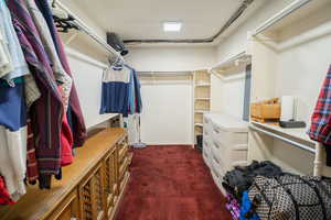 Walk in closet featuring dark colored carpet