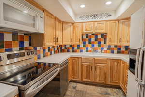 Kitchen with appliances with stainless steel finishes, decorative backsplash, recessed lighting, and tile counters