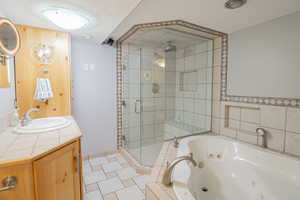 Full bathroom with a whirlpool tub, vanity, a stall shower, and light tile patterned flooring
