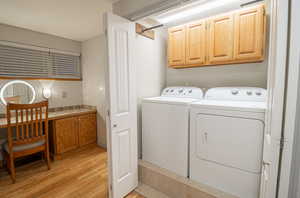 Washroom featuring light wood finished floors, cabinet space, and washer and dryer