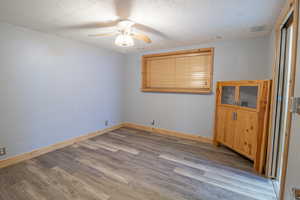Unfurnished room with a textured ceiling, light wood finished floors, and a ceiling fan