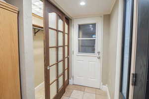Doorway with tile patterned flooring, crown molding, and a textured wall