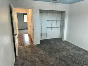 Unfurnished bedroom featuring dark carpet and a closet