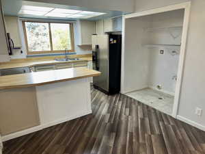 Kitchen with light countertops, appliances with stainless steel finishes, a peninsula, dark wood-style floors, and white cabinets