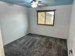 Empty room with dark colored carpet and ceiling fan