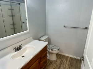 Full bath with vanity, tiled shower, and dark wood-style floors