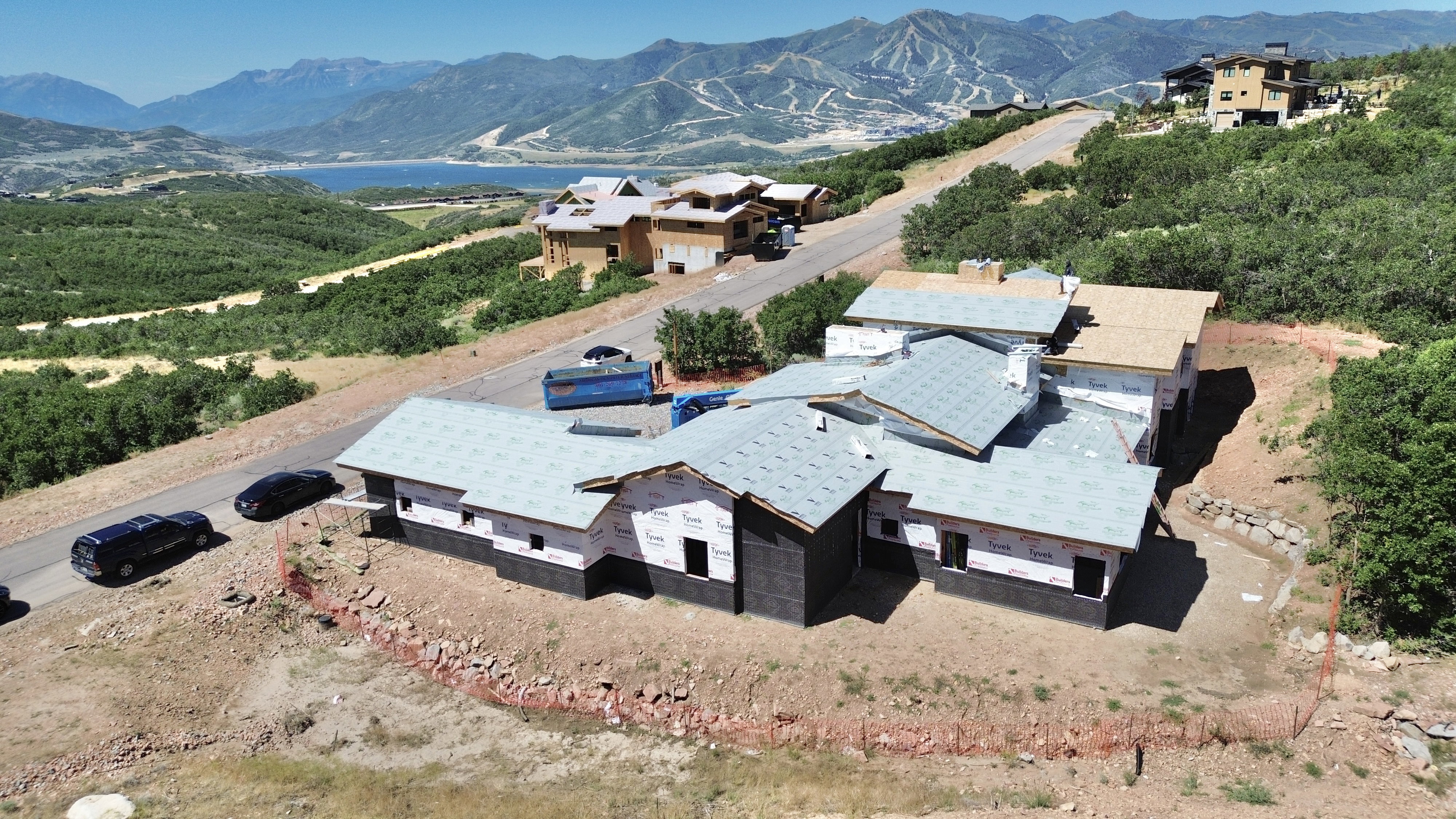 New construction property featuring a multi-level roofline, partial exterior sheathing, and a surrounding natural landscape
