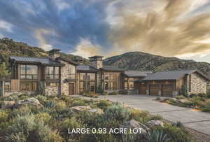 Contemporary home featuring a standing seam roof, stone siding, an attached garage, concrete driveway, and a chimney