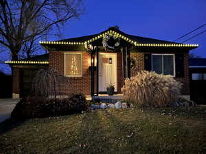 View of front of home featuring a lawn, brick siding, a garage, and driveway