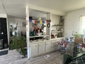 Kitchen featuring white cabinetry, light countertops, light wood-style floors, built in desk, and open shelves