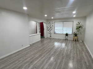 Spare room with arched walkways, light wood-style floors, and recessed lighting