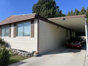 View of property exterior featuring an attached carport and concrete driveway