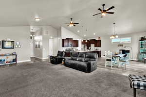 Living area with a chandelier, high vaulted ceiling, a ceiling fan, and light carpet