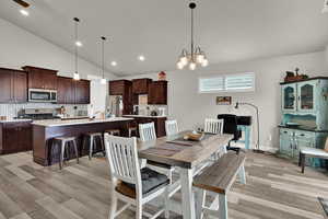 Dining room with vaulted ceiling, light wood-type flooring, a chandelier, and recessed lighting