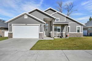 Craftsman house with stone siding, board and batten siding, driveway, a front lawn, and a garage