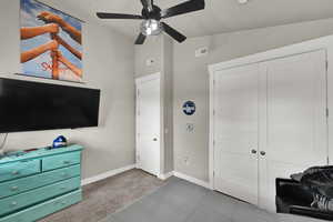 Bedroom with light colored carpet, ceiling fan, light tile patterned flooring, high vaulted ceiling, and a closet