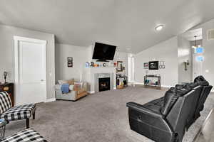 Carpeted living area featuring vaulted ceiling and a premium fireplace