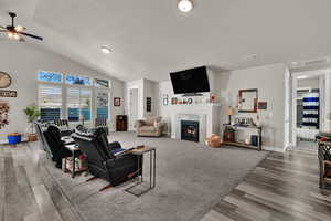 Living area featuring a premium fireplace, vaulted ceiling, and light wood-style flooring