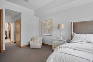 Carpeted bedroom featuring a barn door and baseboards