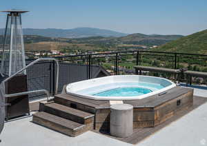 View of pool with a hot tub, a mountain view, and a patio