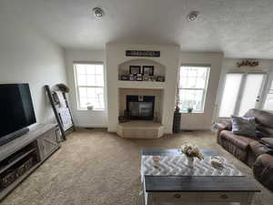 Carpeted living area featuring a textured ceiling and a fireplace