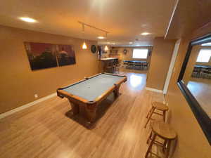 Game room featuring billiards table, light wood-type flooring, and a dry bar