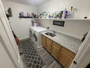 Laundry area with dark wood-type flooring, independent washer and dryer, and cabinet space