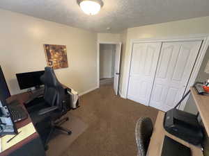 Office area with carpet flooring and a textured ceiling