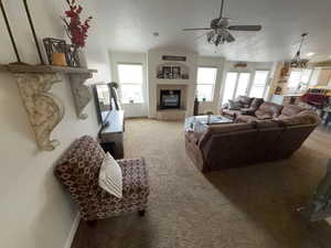 Carpeted living room featuring a tile fireplace and a ceiling fan