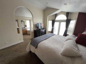 Carpeted bedroom featuring lofted ceiling, a textured ceiling, access to exterior, and connected bathroom