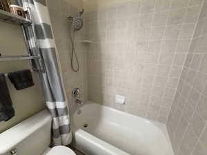 Full bathroom with shower / bathtub combination with curtain and toilet