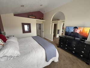 Carpeted bedroom featuring vaulted ceiling and a textured ceiling