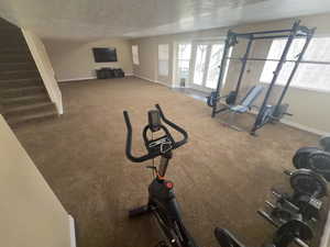 Exercise area with a textured ceiling and carpet floors