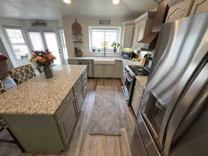 Kitchen featuring stainless steel appliances, a kitchen breakfast bar, decorative backsplash, light wood-type flooring, and a center island