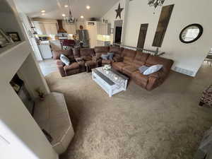 Living room featuring light carpet, a chandelier, recessed lighting, high vaulted ceiling, and a glass covered fireplace