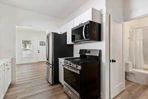 Kitchen featuring stainless steel range with gas stovetop, white cabinetry, and light wood-style flooring