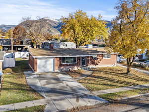 View of front of property with brick siding, a chimney, driveway, and a mountain view