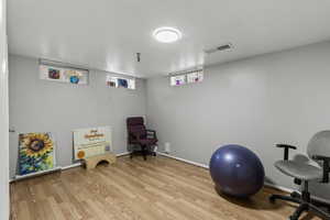 Workout area with light wood-type flooring and baseboards