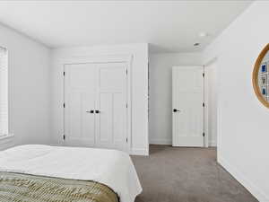 Carpeted bedroom with baseboards and a closet