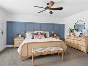 Carpeted bedroom featuring a decorative wall and a ceiling fan