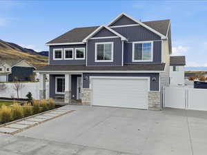 Craftsman-style house with stone siding, a shingled roof, driveway, and a garage