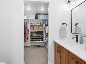 Bathroom with vanity, light carpet, and a walk in closet