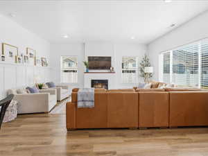 Living area with plenty of natural light, light wood-style floors, a glass covered fireplace, and recessed lighting