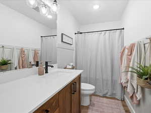 Bathroom with curtained shower, vanity, and light wood-style flooring