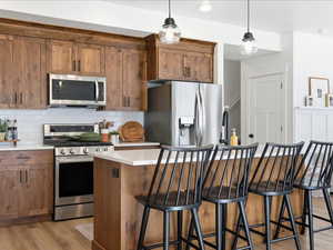 Kitchen featuring stainless steel appliances, a breakfast bar, tasteful backsplash, and brown cabinets