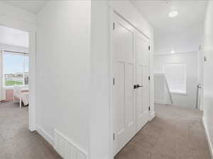 Hallway featuring light carpet