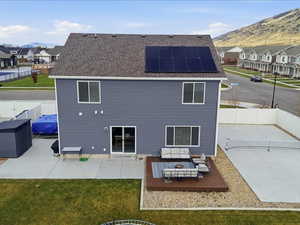 Rear view of property featuring a residential view, a fenced backyard, roof mounted solar panels, and a patio