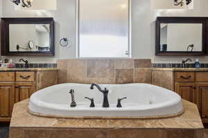 Bathroom featuring a whirlpool tub and two vanities