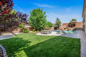 Fenced backyard featuring a patio area and a pool with connected hot tub