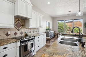 Kitchen featuring dark stone counters, stainless steel range with electric cooktop, decorative light fixtures, decorative backsplash, and a textured ceiling